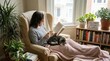 © Bogdan - Woman reading a book in a cozy armchair with a cat on her lap. Solitary leisure at home