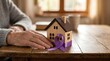 © Alex - Senior hand resting by a wooden house with a purple ribbon