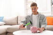 © New Africa - Man breaking piggy bank with hammer and coins at white table indoors, space for text