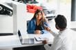 © Serhii - Indian woman receiving car keys from salesman in showroom