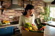 © Davor - Woman unpacking organic vegetable delivery at home kitchen