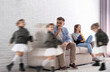 © New Africa - Family with hyperactive child. Tired parents sitting on sofa while their daughter having fun