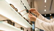 © CK Studio - Sunglasses customer hands selecting eyewear from display shelf in optical store for fashion or retail shopping experience.