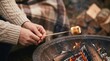 © velikiyzayats - Young woman roasting marshmallow over backyard fire pit for cozy autumn camping lifestyle concept