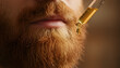 © Garnibi Mind Studio - Close-up of a man applying nourishing golden oil to his red beard using a glass dropper for daily grooming and skin care routine.