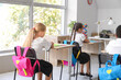© Pixel-Shot - Little classmates sitting at desks in classroom during lesson