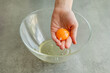 © Adriana Nikolova - Close-up of a child's hands carefully separating an egg yolk from the egg white using their fingers over a bowl