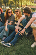 © master1305 - Young friends laughing on grass in sunny park with retro effect. Concept of carefree friendship, summer leisure, youth lifestyle, outdoor bonding, and nostalgic social mood.