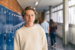 © Maskot - Portrait of junior high male student standing near locker in school lobby