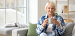 © Pixel-Shot - Senior woman with cup of tea sitting on sofa at home