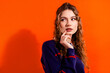 © deagreez - Thoughtful young woman in a navy sweater posing against a vibrant orange studio background for a fashion portrait and beauty headshot
