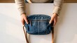 © Aliaksandra - Blue Denim Shoulder Bag Held by Man on White Tabletop for E-commerce Fashion Banner