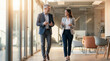 © Aurora Aesthetics - office mentorship coaching mentor mentee walking career guidance leadership support senior executive and young professional walk through bright corridor discussing goals progress and next
