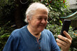 © Carlos Eduardo - Adulto mayor feliz usando un teléfono inteligente al aire libre