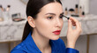 © Aurora Aesthetics - beauty skincare makeup brows young woman ivory skin cosmetics routine ivory skinned woman sharpens brow shape with slim tool in refined bathroom and classic red lip styling designed for beauty