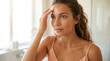 © Aurora Aesthetics - beauty skincare makeup skincare young woman tan skin cosmetics routine tan skinned woman touches forehead while assessing smooth skin in clean bathroom with natural confidence designed for beauty