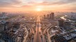 © Iwan - Aerial view of a sprawling cityscape with busy highway interchange during a beautiful sunset, showcasing ongoing urban development and infrastructure projects