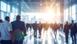 © Gang - A blurred image of people walking in a large, brightly lit hall with shiny floor
