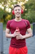 © New Africa - Portrait of young man in sportswear with headphones and bottle of water at outdoor gym