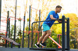 © New Africa - Young man exercising on manual treadmill at outdoor gym, low angle view. Space for text