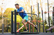 © New Africa - Young man exercising on manual treadmill at outdoor gym, low angle view