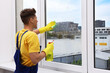 © New Africa - Man washing window with rag and detergent indoors