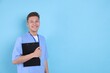 © New Africa - Medical assistant with clipboard on light blue background. Space for text