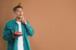 © New Africa - Man holding piece of cake with burning candle on brown background, space for text