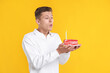 © New Africa - Man blowing candle on piece of delicious cake against orange background