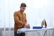 © New Africa - Man folding t-shirt at ironing board indoors
