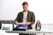 © New Africa - Man stacking clean clothes on ironing board at home