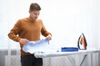 © New Africa - Man folding t-shirt at ironing board indoors