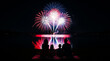 © Studio Fiuza - Family watches colorful fireworks display over lake at night from picnic blanket