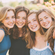 © Anneleven - Four happy young women smiling close together, embracing, and enjoying friendship outdoors in summer sunshine