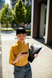© Davor - Young professional woman texting while walking on city campus