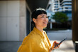 © Davor - Smiling woman using smartphone outdoors in modern city