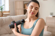© Pixel-Shot - Sporty young woman with percussive massager at home, closeup