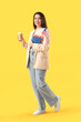 © Pixel-Shot - Young woman with USA flag, books and cup of coffee on yellow background