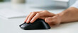 © S-DESIGN - Close-up of a person's hand using a computer mouse on a white desk. The focus is on the interaction with technology and the work environment.