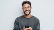 © RndVisuals - Young man with glasses and beard smiling while holding a smartphone against a white background