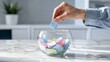 © Amith - Hand Placing Colorful Paper Notes into Glass Bowl on Blue Background – Choice, Decision Making, Lottery, Voting and Random Selection Concept