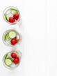 © Bogdan - High key flat lay of healthy detox infused water glasses on white table with copy space.