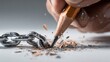 © Mikhail Vorobev - Hand sharpening a pencil to symbolically break a strong metal chain link with flying shavings of wood and graphite in a conceptual close-up image