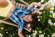 © TrueShot | Westend61 - Relaxing on a deck chair in a summer garden full of daisies