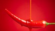 © photostockatinat - A vibrant red chili pepper with a glossy sauce drizzled over it, set against a bold red background. The image evokes a sense of heat and intensity