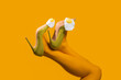 © VISTA by Westend61 - Surreal legs in green heels with eggs on top against yellow background