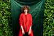 © VISTA by Westend61 - Model in a bright blazer posing outdoors in a green garden