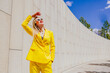 © VISTA by Westend61 - Happy freelancer in yellow suit shielding eyes from sun outdoors