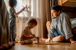 © Westend61 - Father sitting on floor with sons playing at home
