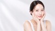 © YT - 静かなライトグレーの空間で両手に顔を包み込み、澄んだまなざしとつややかな素肌を印象的に見せる若い女性。まとめ髪と白いノースリーブが清潔感を引き立て、保湿ケア、敏感肌向けスキンケア、透明感訴求の化粧品広告、フェイスケアブランド、エステや美容サロンのビジュアルに使いやすい上品な人物素材